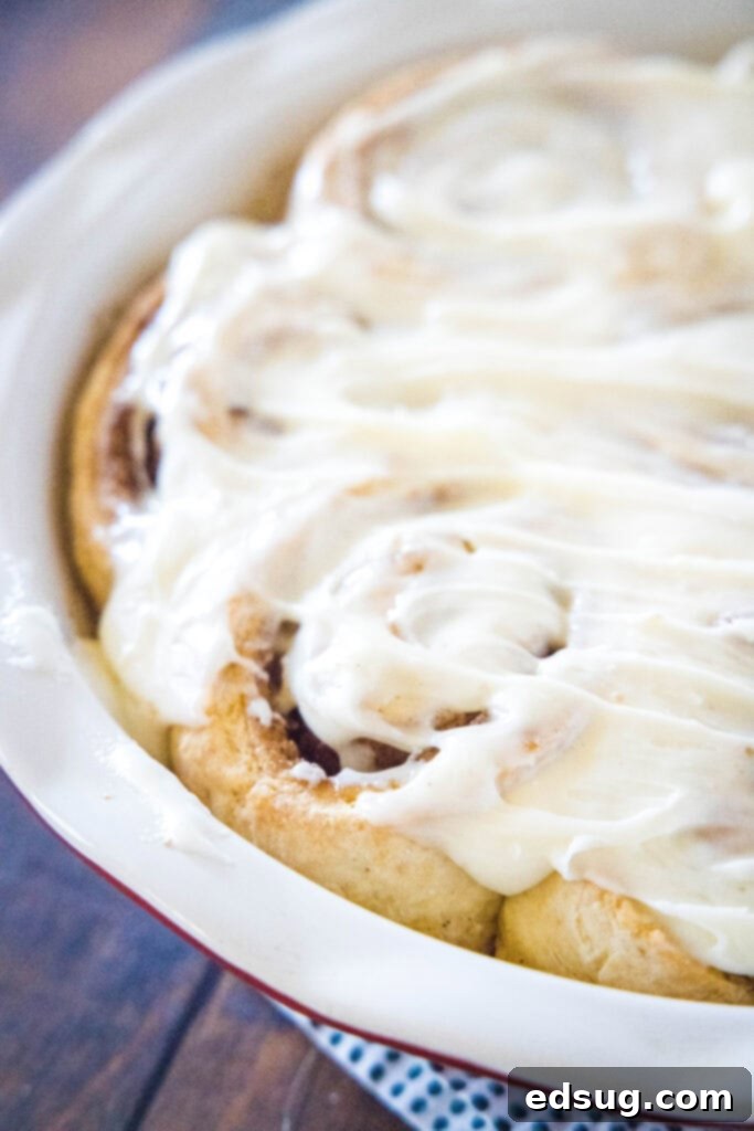 Festive Eggnog Cinnamon Rolls 3 eggnog cinnamon rolls baked in a round baking dish, generously covered with icing.