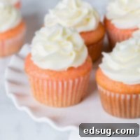strawberry almond cupcakes topped with frosting on a cake stand