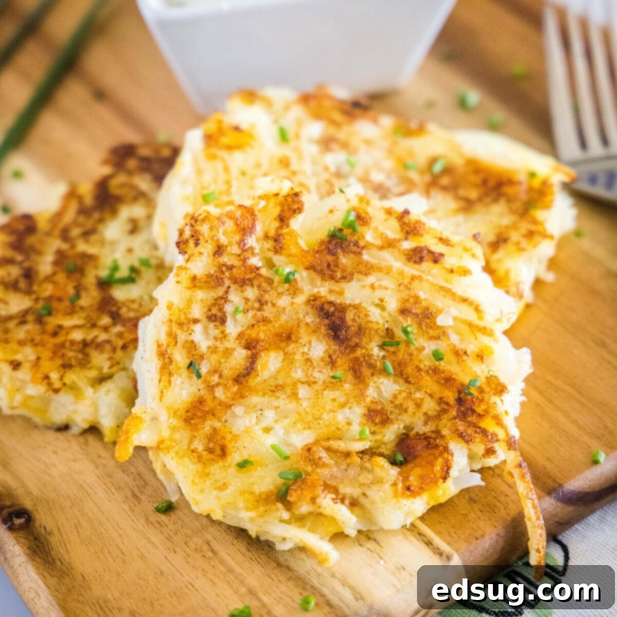 These easy cauliflower fritters are packed with hash browns and cheddar cheese, and served with a creamy and tart dipping sauce. Close up of two cauliflower fritters in a stack, next to a fork