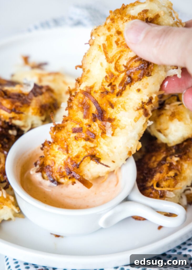 dipping coconut chicken tenders into canes sauce