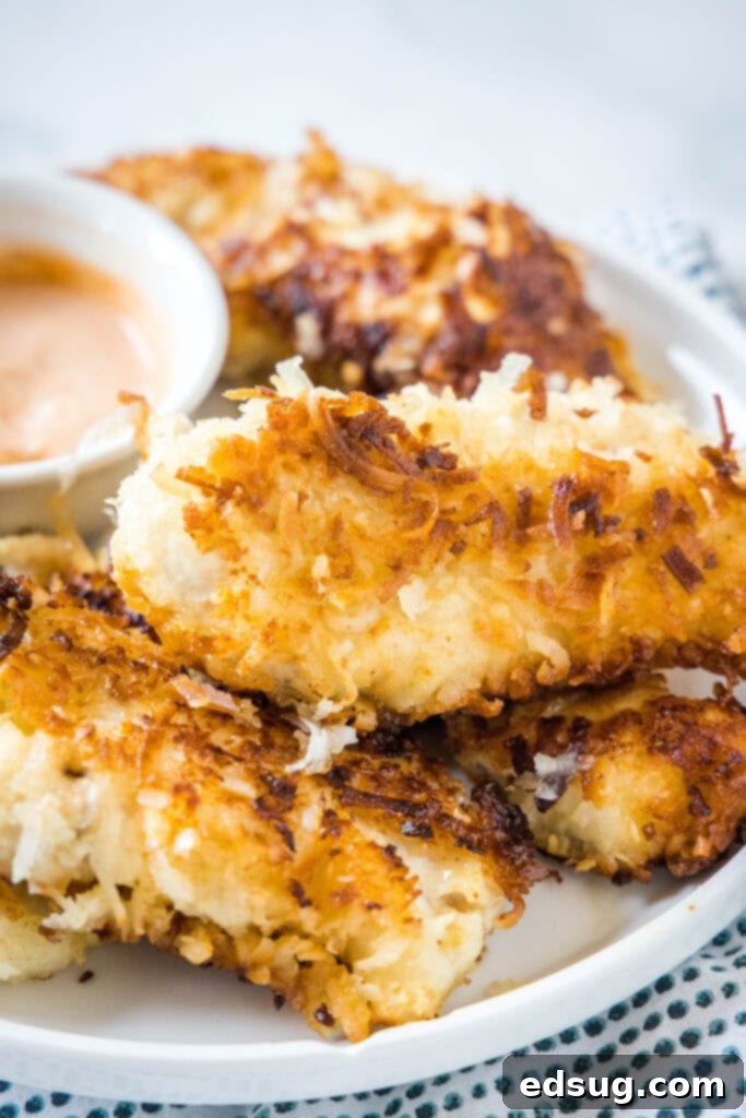 a white plate stacked with coconut crusted chicken tenders