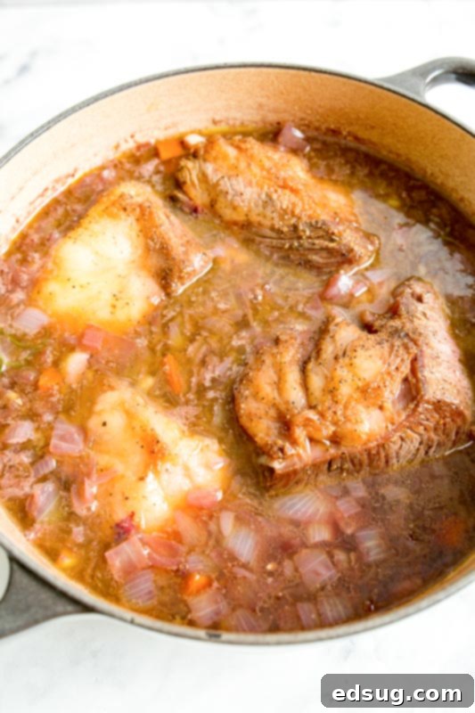 Fork-Tender Red Wine Short Ribs 3 short ribs in cooking liquid in dutch oven