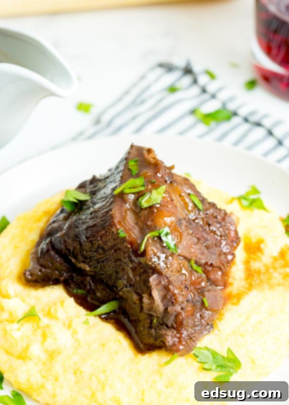 Fork-Tender Red Wine Short Ribs 7 polenta on a plate with beef rib over it