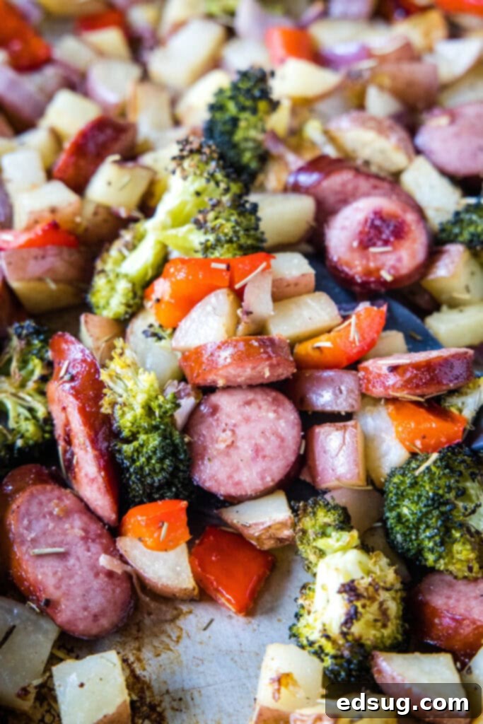 Flavorful One-Pan Sausage and Potatoes 6 A close-up of a baking tray filled with perfectly roasted sausage and potatoes, golden brown and garnished with fresh herbs, ready to be served.