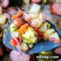 Flavorful One-Pan Sausage and Potatoes 8 A close-up image of a spatula scooping up crispy roasted potatoes and vegetables, part of the delicious sheet pan meal.